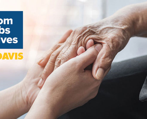 A younger hand gently holds an older hand, conveying care and support. Beside them, a blue square displays the text “From Labs to Lives” above the UC Davis logo.