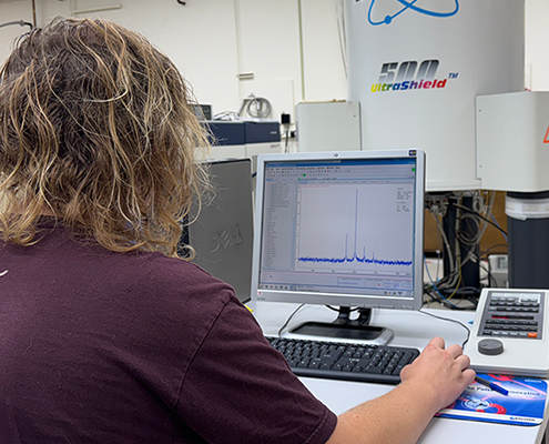 person sitting at a computer with a piece of equipment in front of them