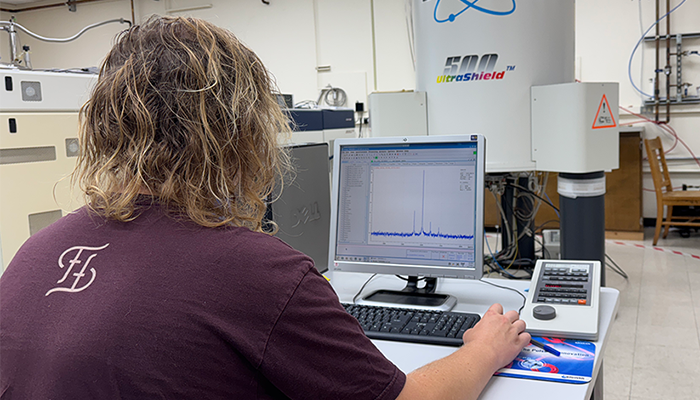 person sitting at a computer with a piece of equipment in front of them