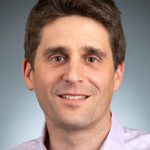 Head shot of smiling man with brown hair and white shirt