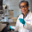 Researcher in white coat and blue gloves works in laboratory