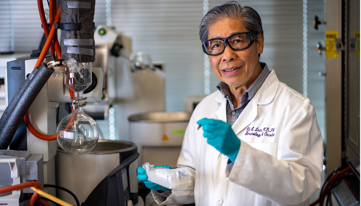 Researcher in white coat and blue gloves works in laboratory