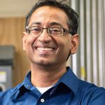 Headshot of smiling man with glasses in dark blue shirt