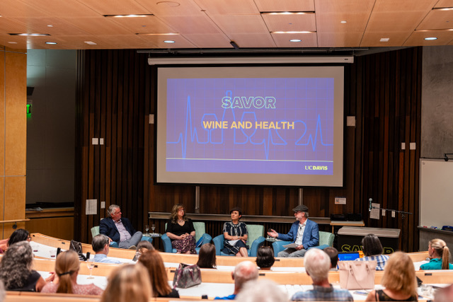 A panel of four speakers discusses “SAVOR: Wine and Health” in a UC Davis lecture hall as the audience listens in.