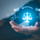 A digital illustration of a hand holding glowing scales of justice between AI and human brain icons, representing fairness in artificial intelligence.