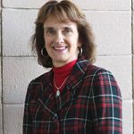 Head and shoulders of white woman with shoulder length brown hair in a red turtleneck with jacket