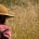 man in long sleeved shirt and hat looking out at a field
