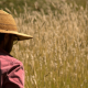 man in long sleeved shirt and hat looking out at a field